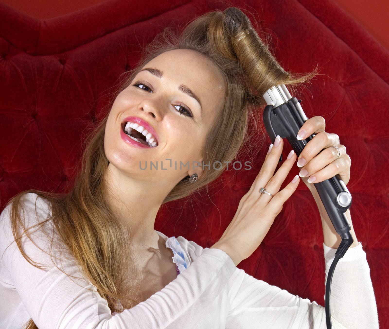 happy beautiful young girl curling her hair