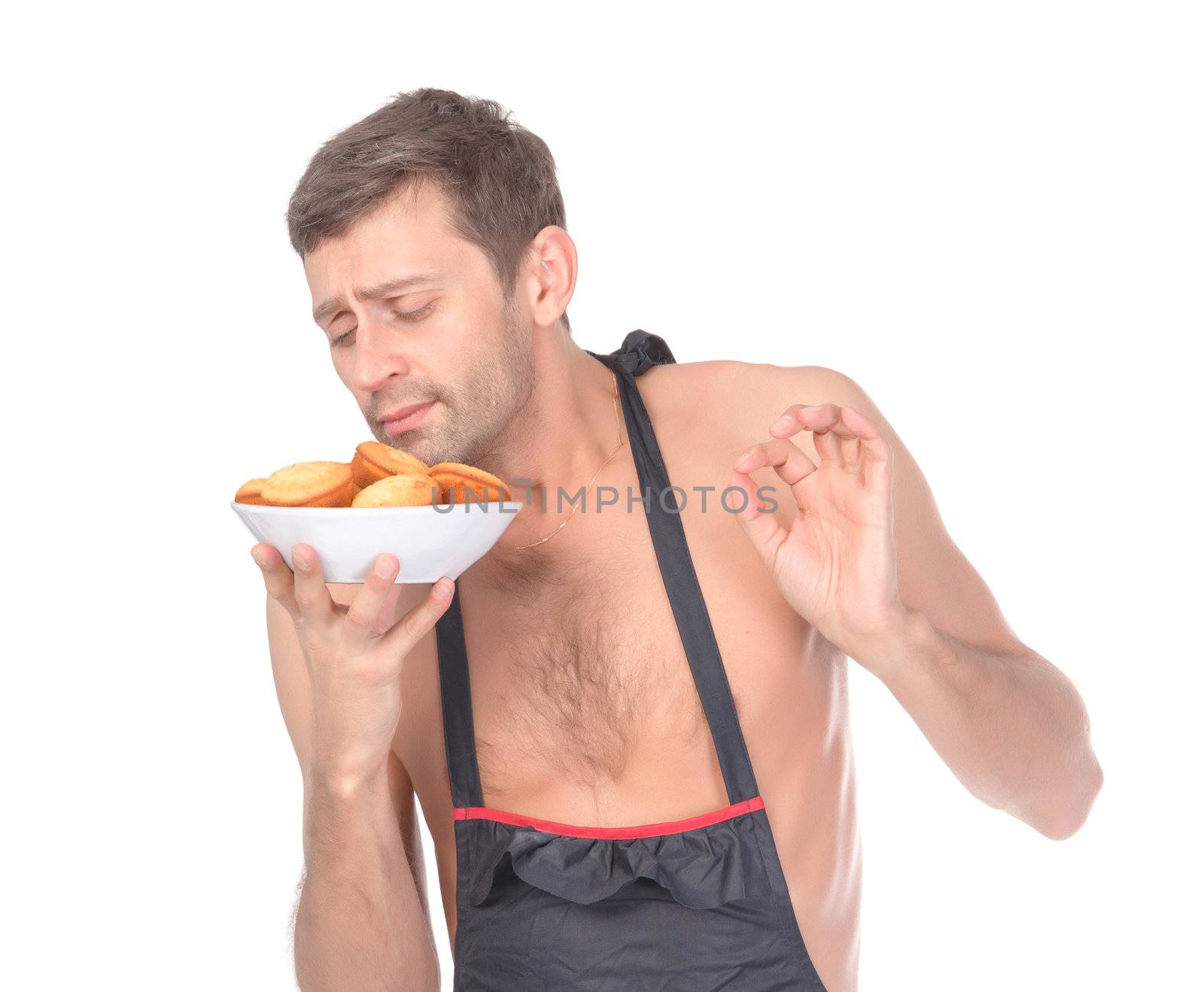 Humorous image of an unshaven shirtless male chef in an apron holding a bowl of cookies and smelling them with a look of pure bliss while making a Superb gesture with his fingers
