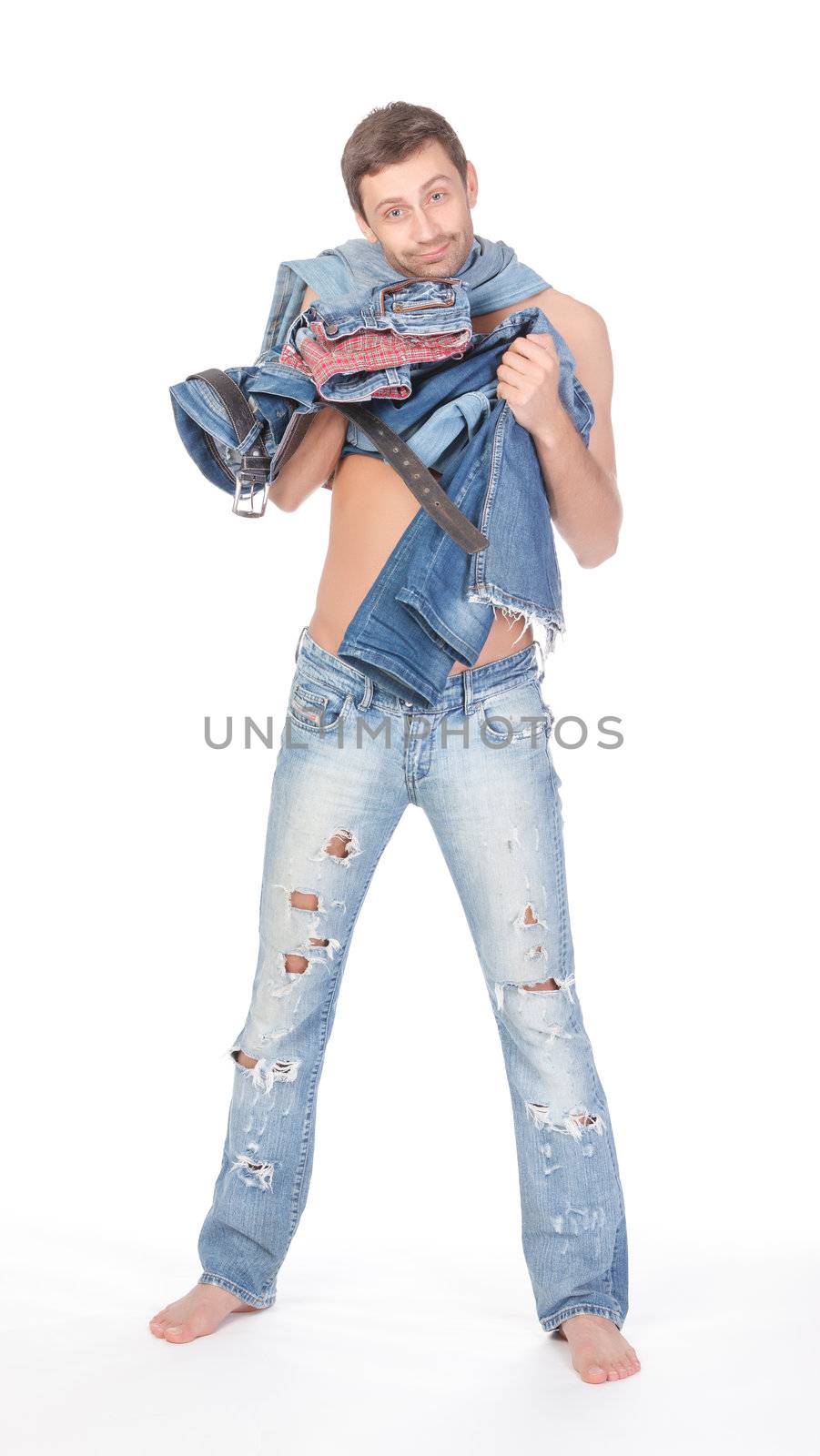 Cool shirtless trendy man in a pair of modern ragged jeans standing deciding what to wear with two pairs of denims in his hands