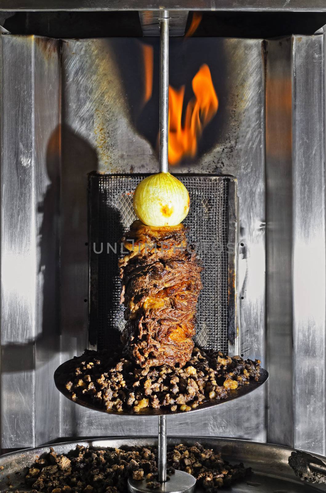 Mixed meat on a vertical spit with whole onion on top