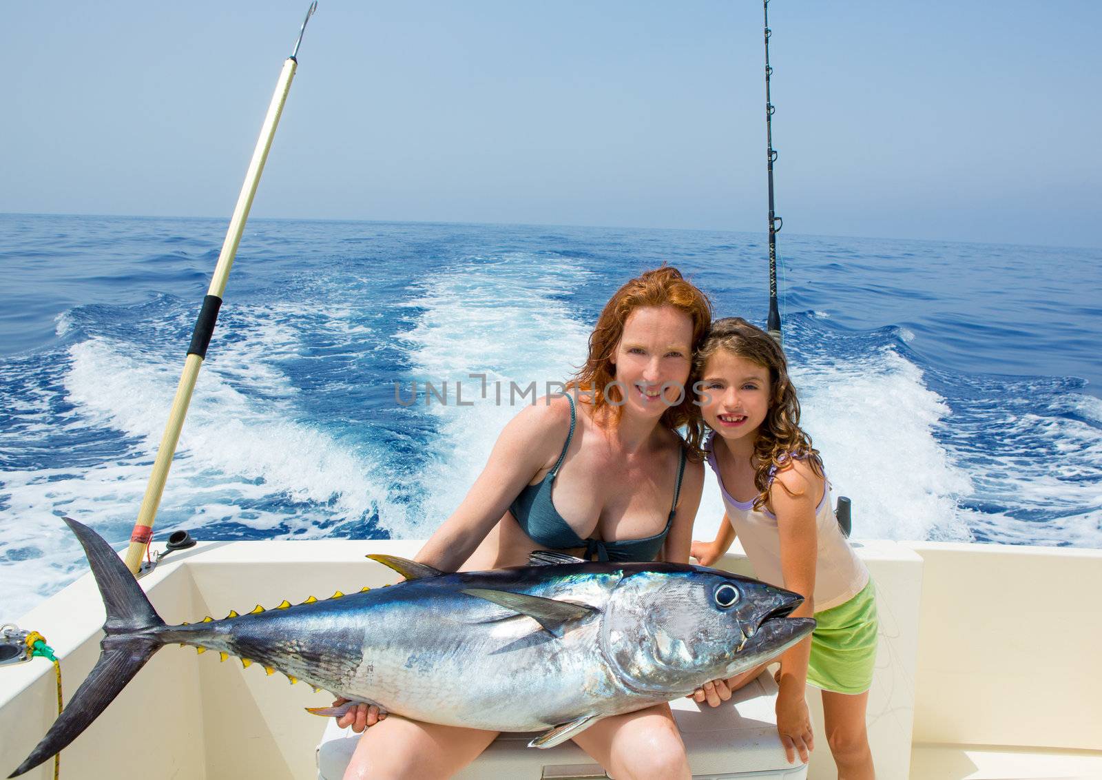 bikini fisher woman and daughter girl holding big bluefin tuna catch on boat deck