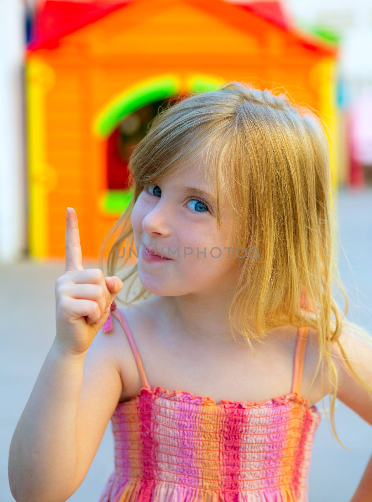 Blond kid girl funny gesture finger up in playground with sundress