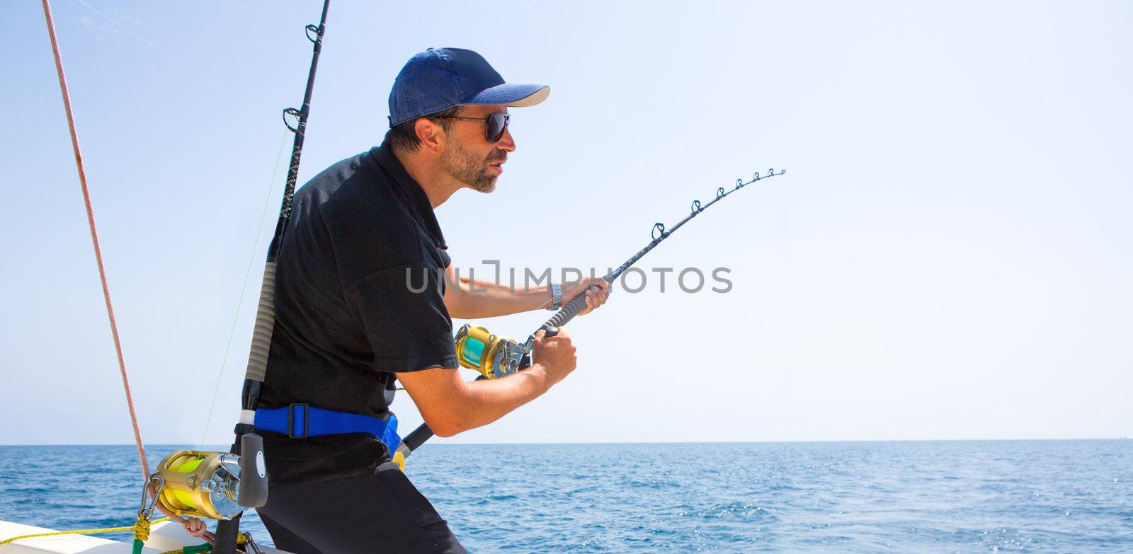 blue sea offshore fishing boat with fisherman holding rod in action