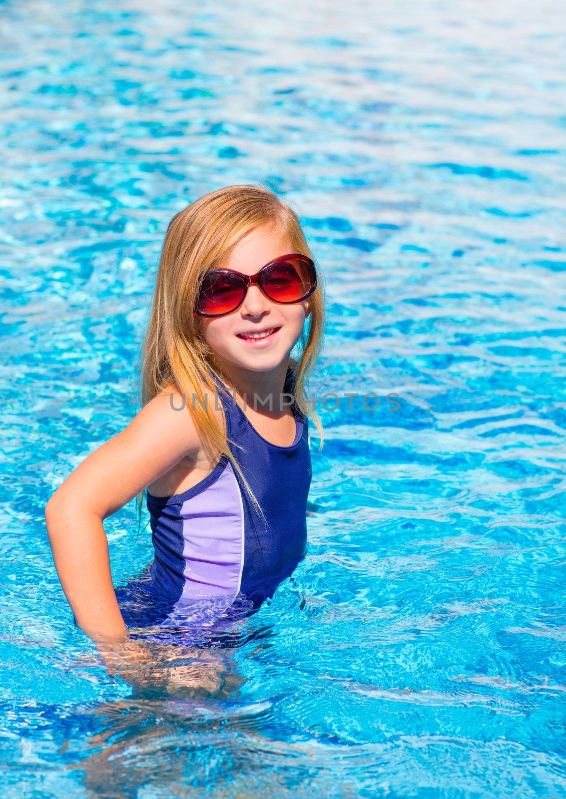 blond kid girl in blue pool posing with sunglasses smiling