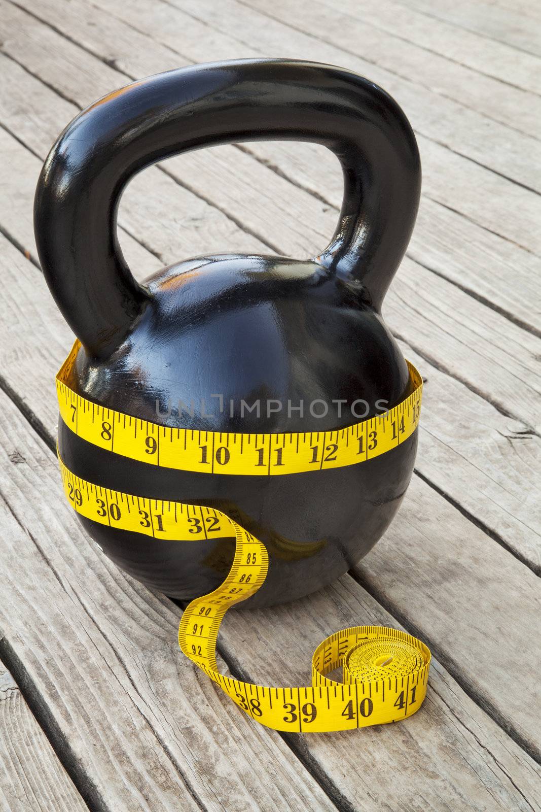 kettlebell and measuring tape on wooden deck - fitness and diet concept