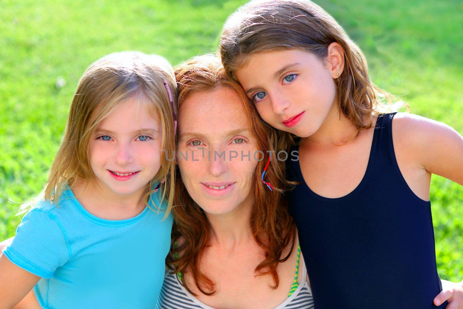mother and two sister daughters in the garden park grass