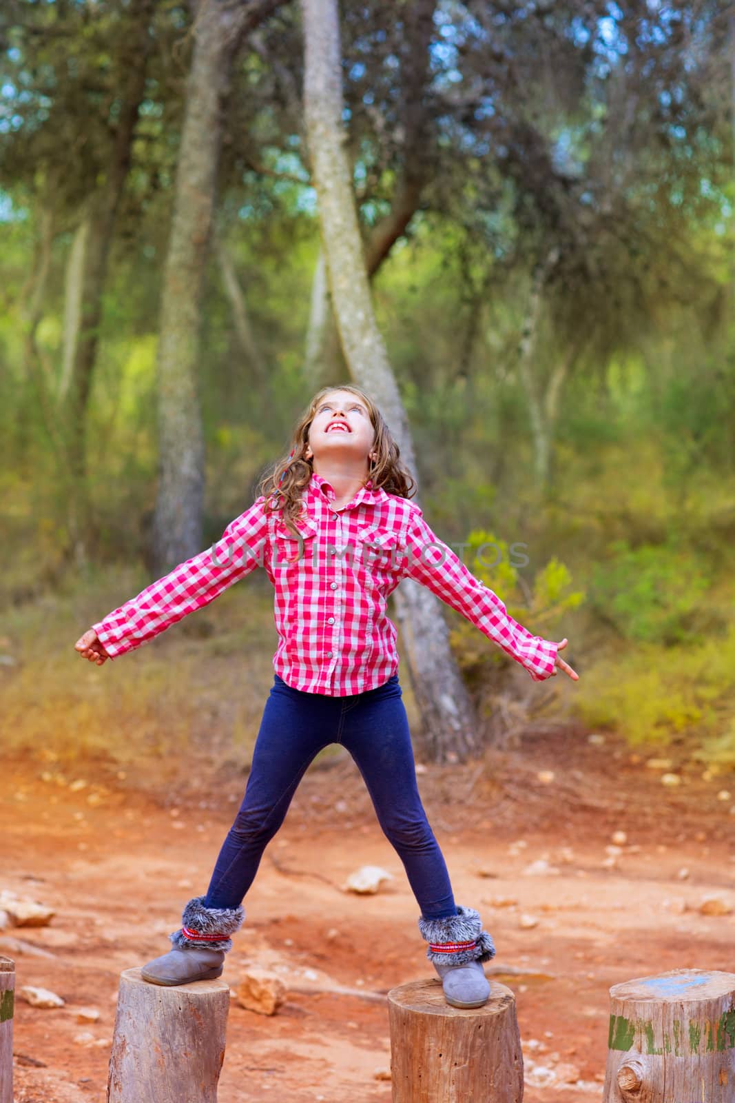 kid girl climbing tree trunks with open arms by lunamarina