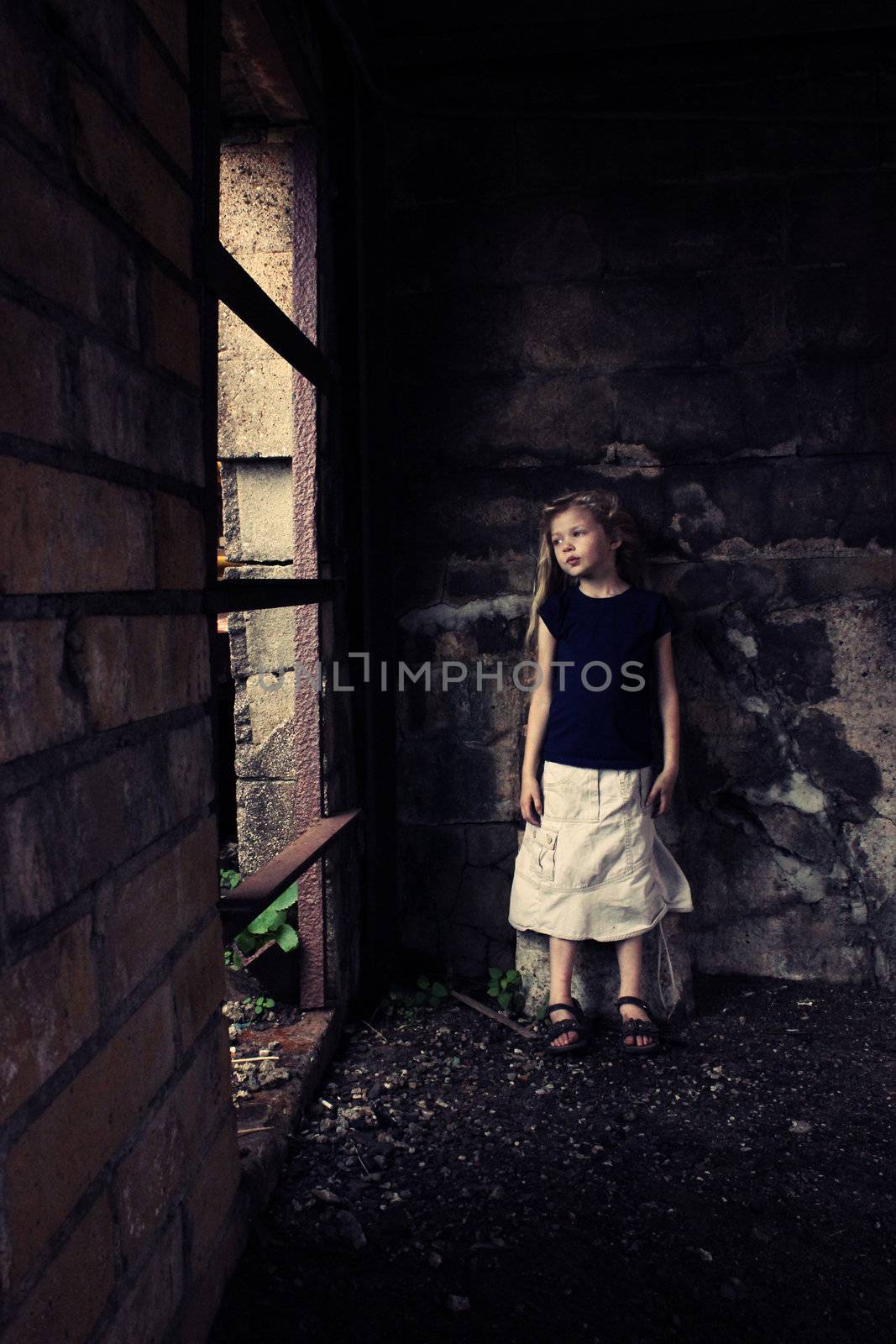 A young girl looking out the window in a grungy building