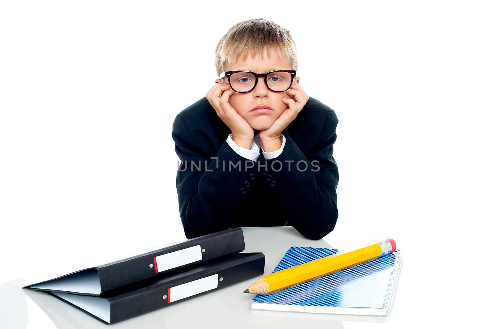 Sad looking boy with hands on his cheeks sitting idle, isolated on white