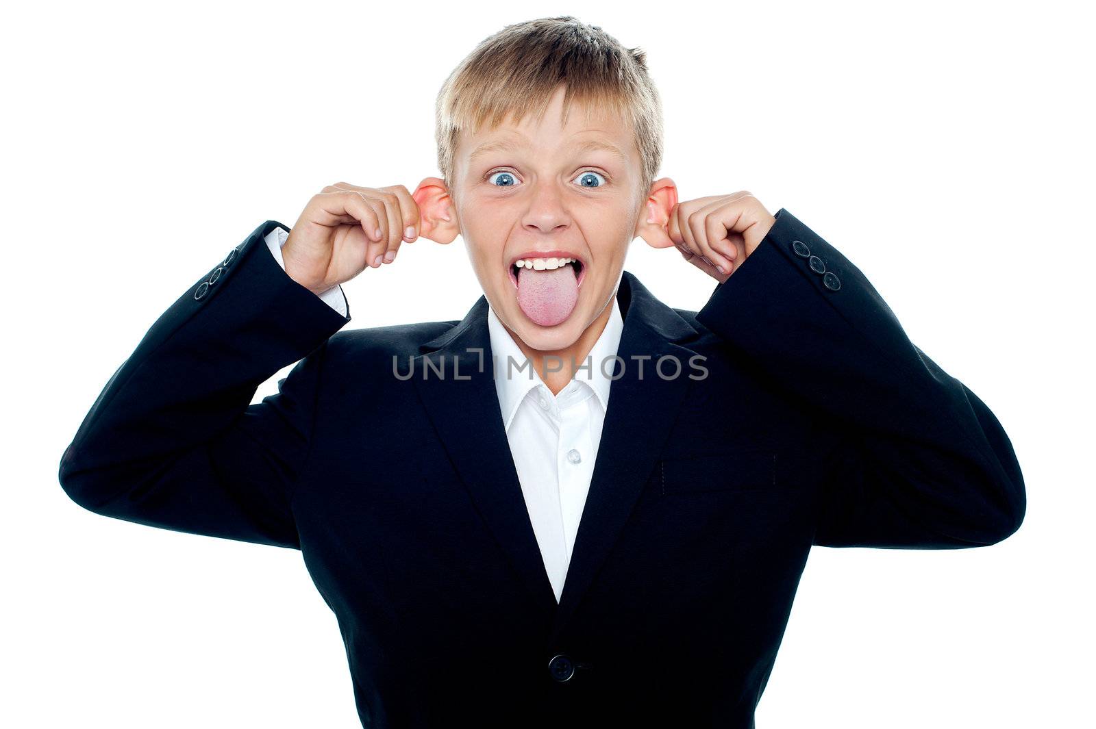 Naughty little boy teasing. Mouth wide open, tongue out and pulling his ears
