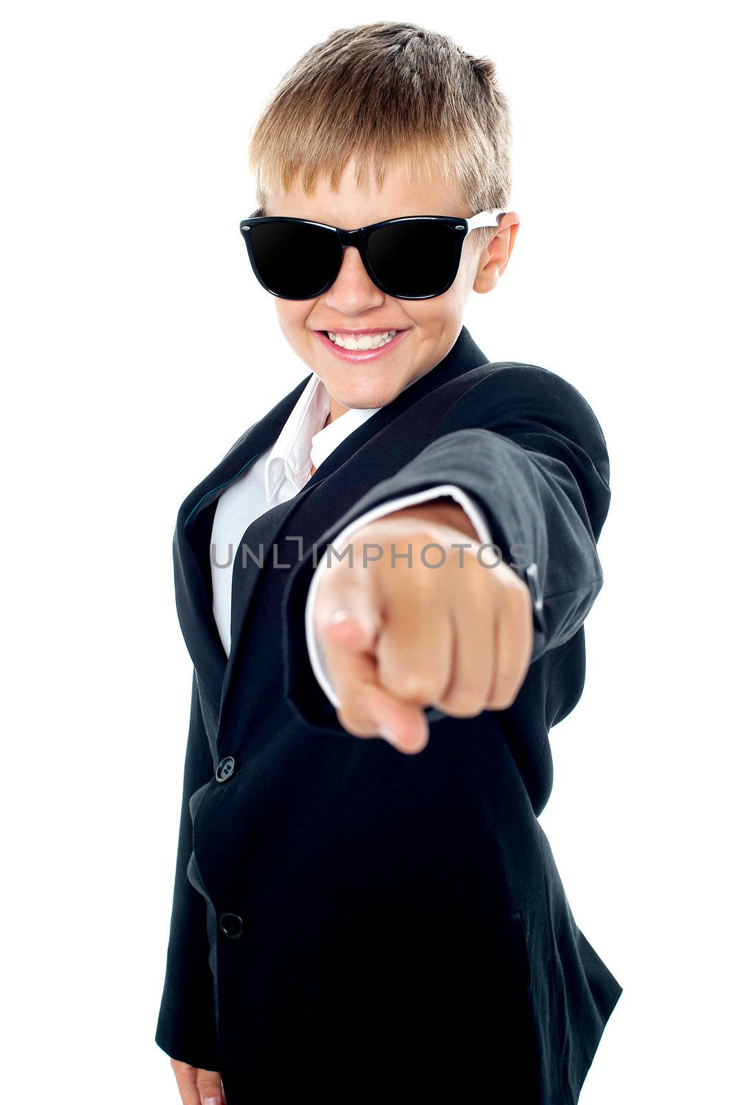 Cheerful young kid pointing towards the camera. Dressed like a businessman