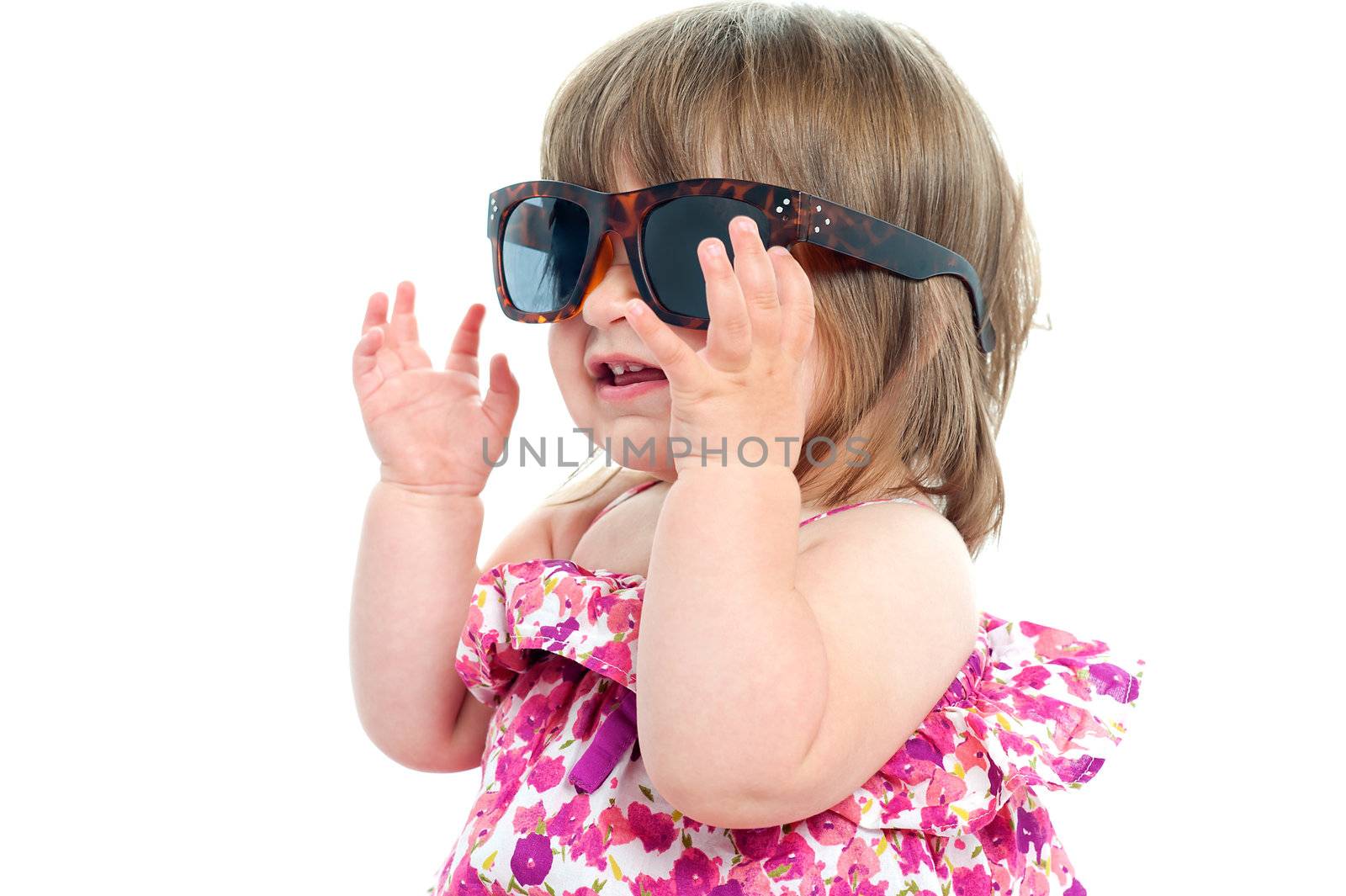 Adorable blonde baby queen adjusting her over sized shades. Closeup shot