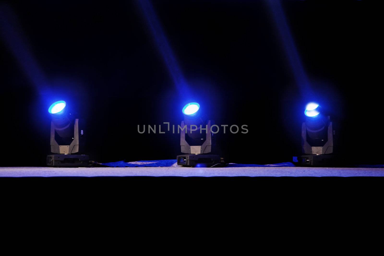 Horizontal capture of blue spot lights on a theater stage pre-curtain raise. Location of shot Goa, India