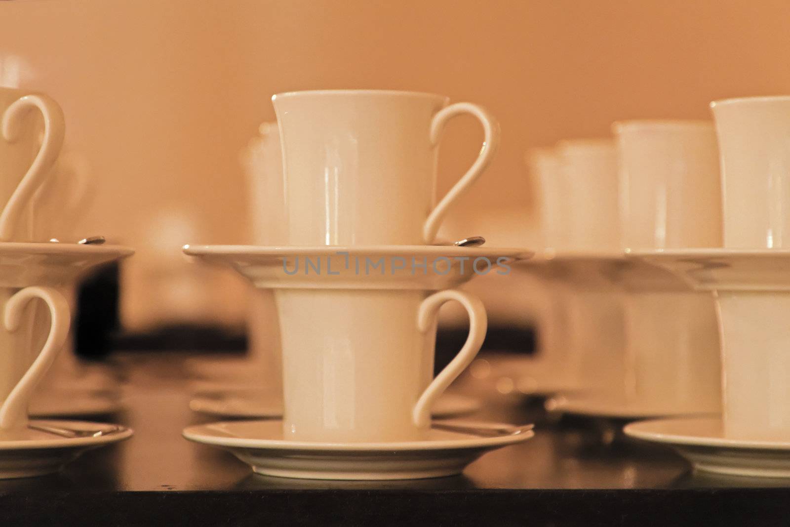 Side elevation of rows Cups Saucers stacked in pairs, warm background. Shot location Bombay studio, India rendered soft focus