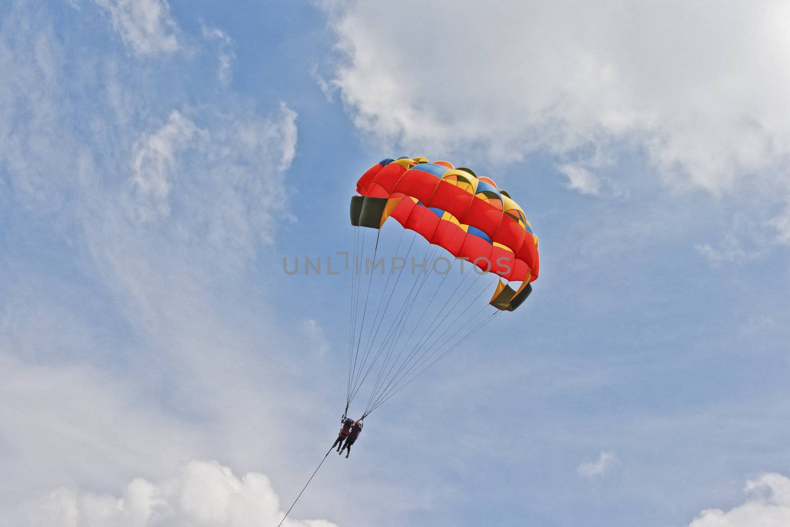 Generic landscape of a pair of female paragliders sailing amongst blue skies and clouds. Location could have been any where but this shot is take in Pachmarhi, Madhya Pradesh, India