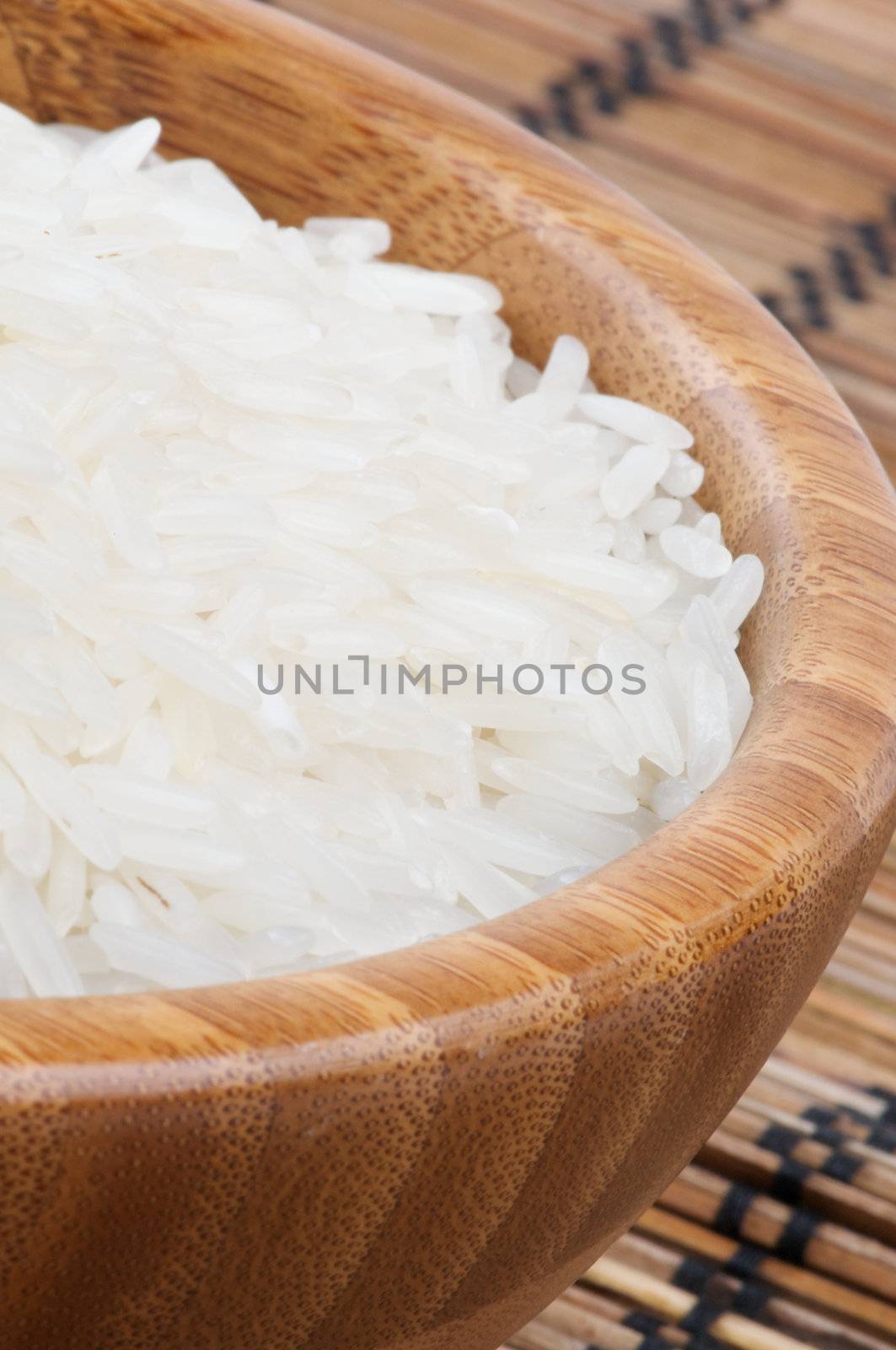 Perfect White Rice in Wooden Bowl closeup on Straw mat background