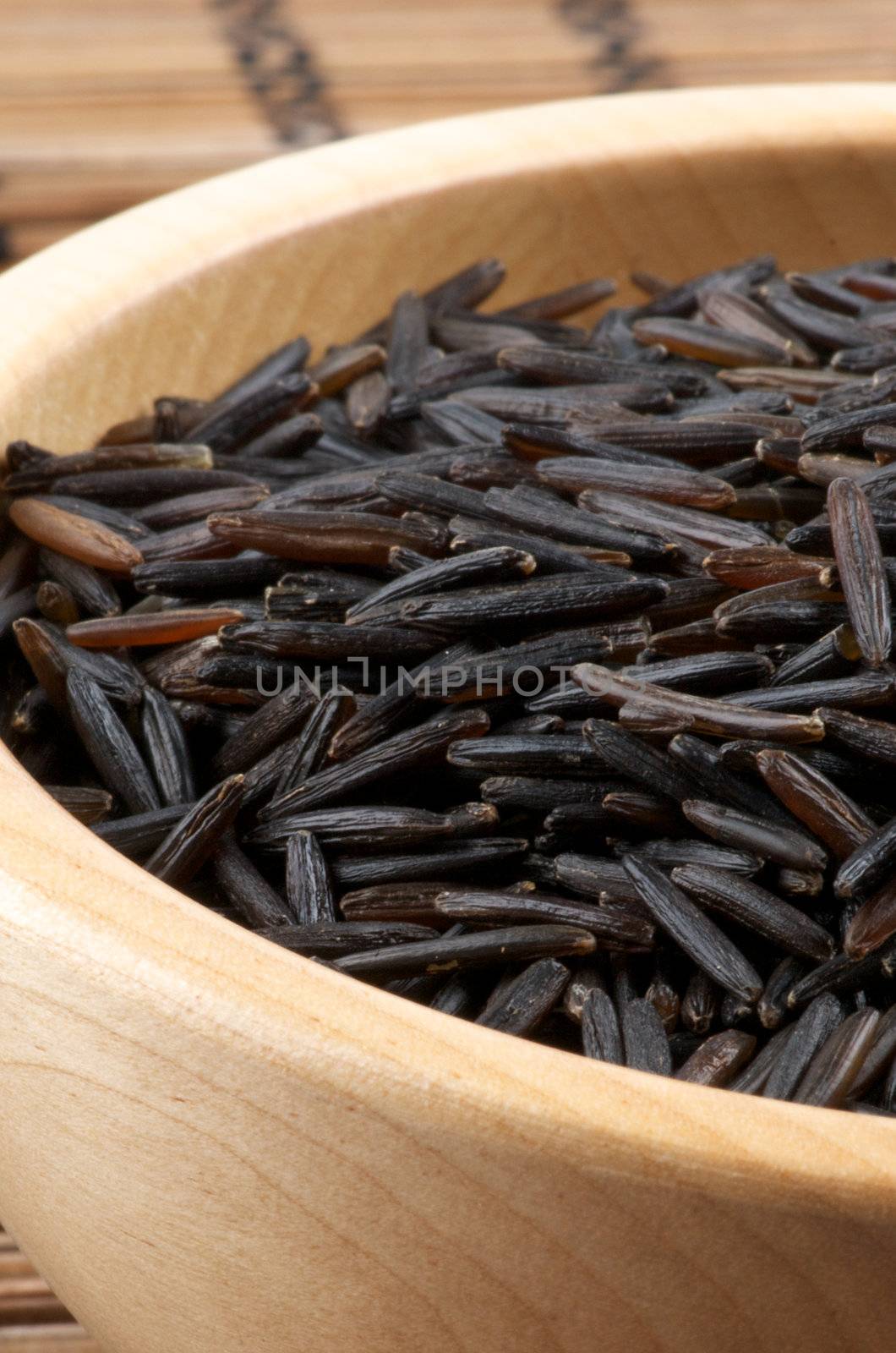 Wood Bowl with Perfect Wild Brown Rice closeup on Straw mat background