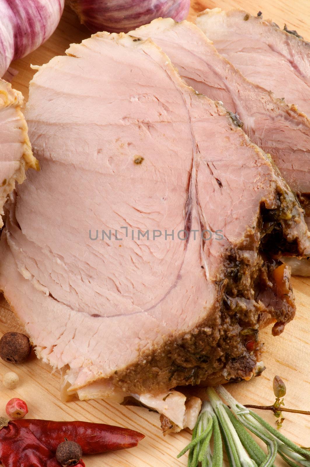 Slices of Juicy Roasted Pork with Spices, Rosemary and Garlic closeup on Cutting Board