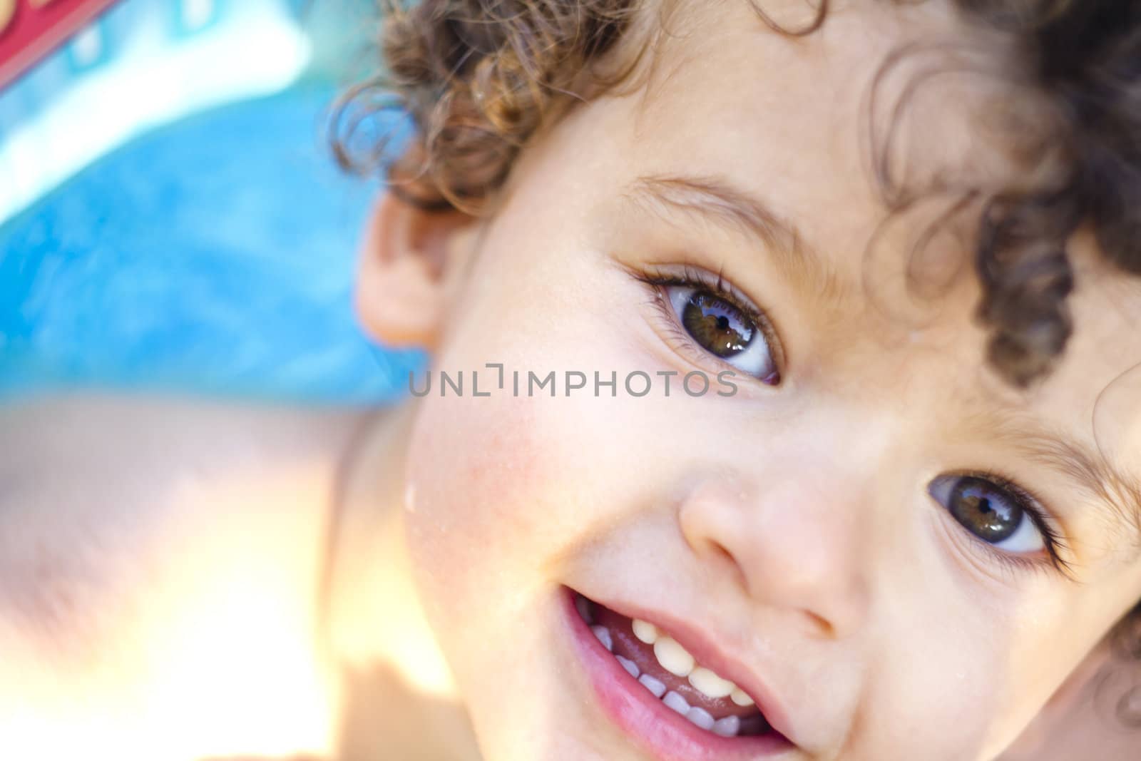 beautiful blond boy with curls at the pool