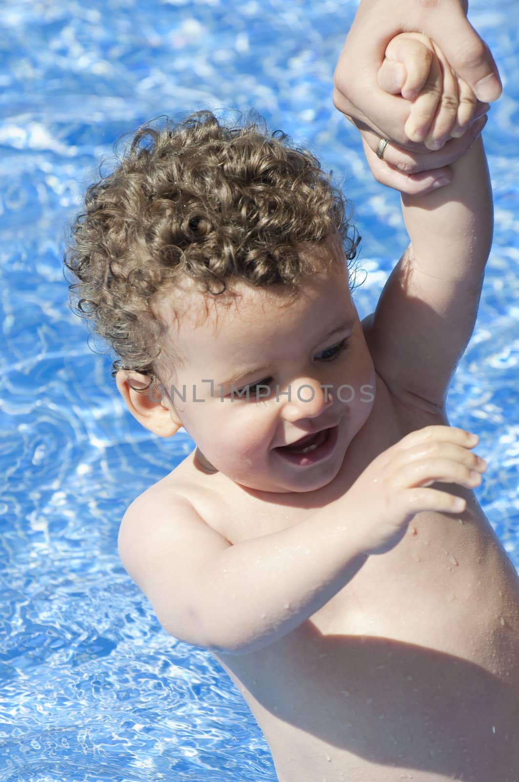 beautiful blond boy with curls at the pool