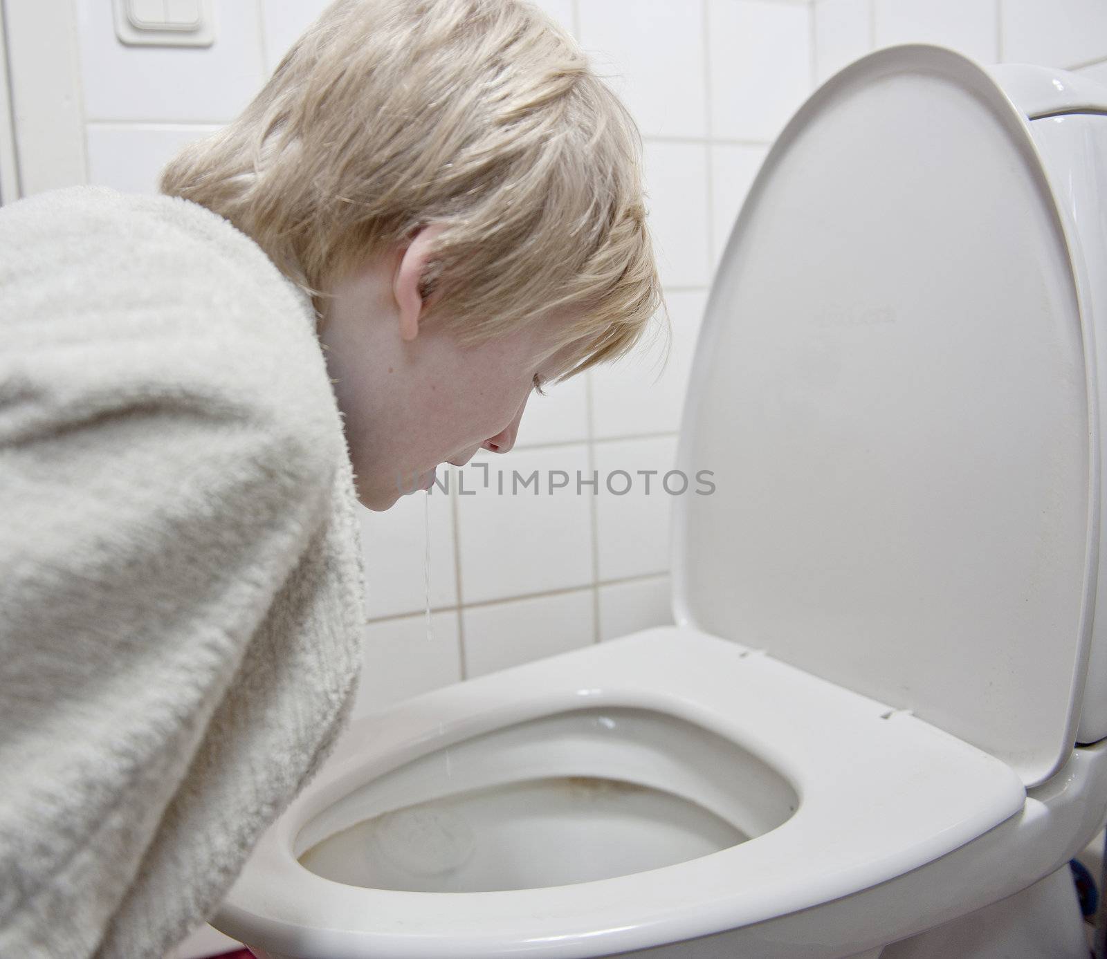 Young boy with stomach flu vomiting in tolilet