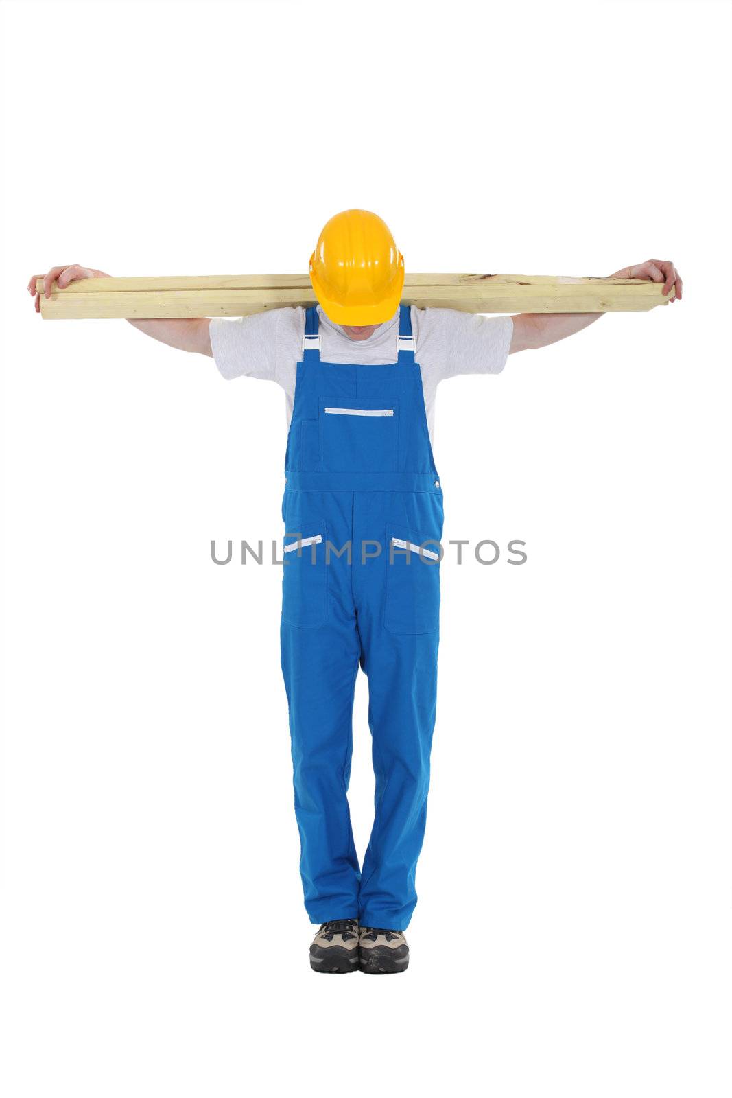 Carpenter with planks of wood along shoulder by phovoir