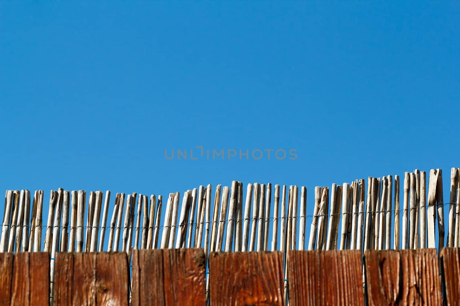 reed fence against blue sky with space for text