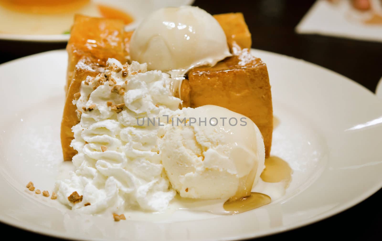 toast with ice cream ,whipping cream and honey syrup on white plate
