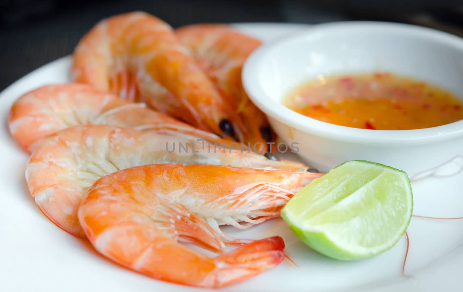 Boiled shrimps on plate served with spicy sauce and lemon
