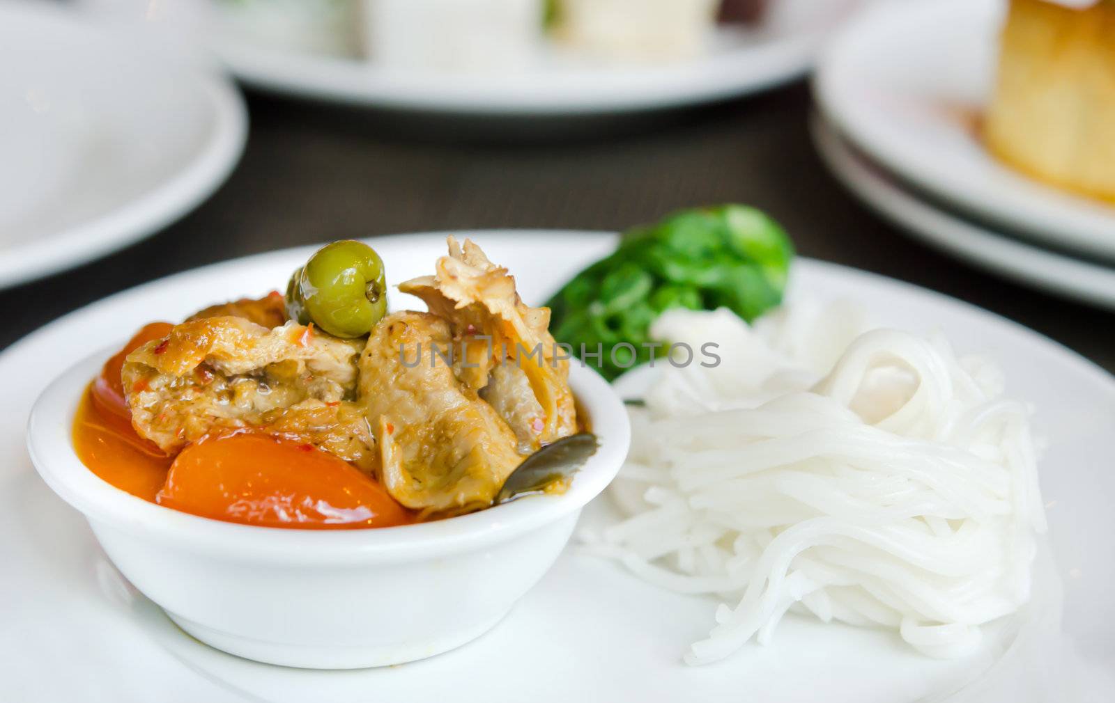 Red curry with roast duck served with vegetable  and rice vermicelli on white plate
