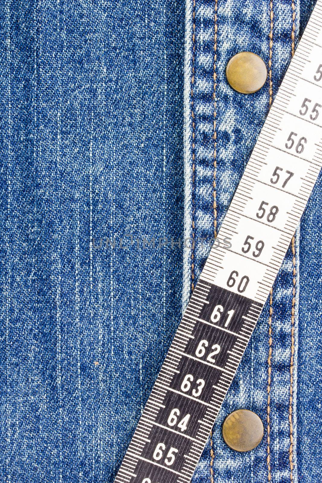Close-up photograph of measuring tape on denim material. Add your text to the background.