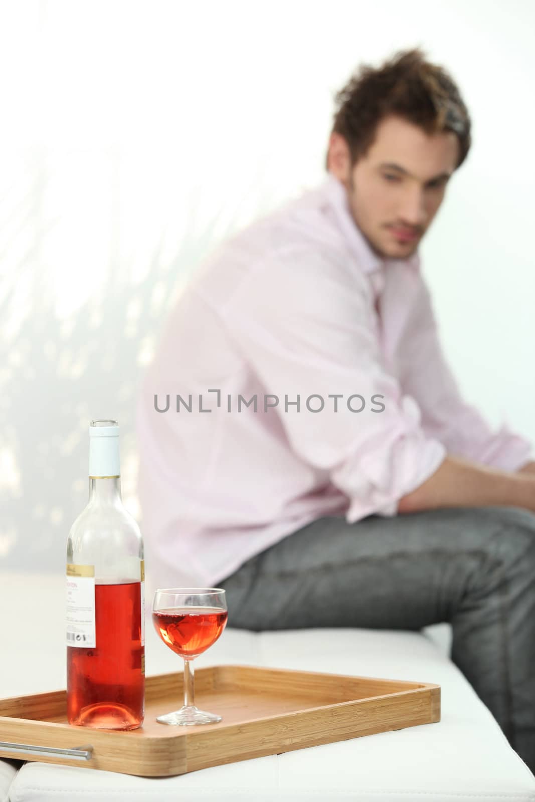 depressed man looking a wine bottle by phovoir