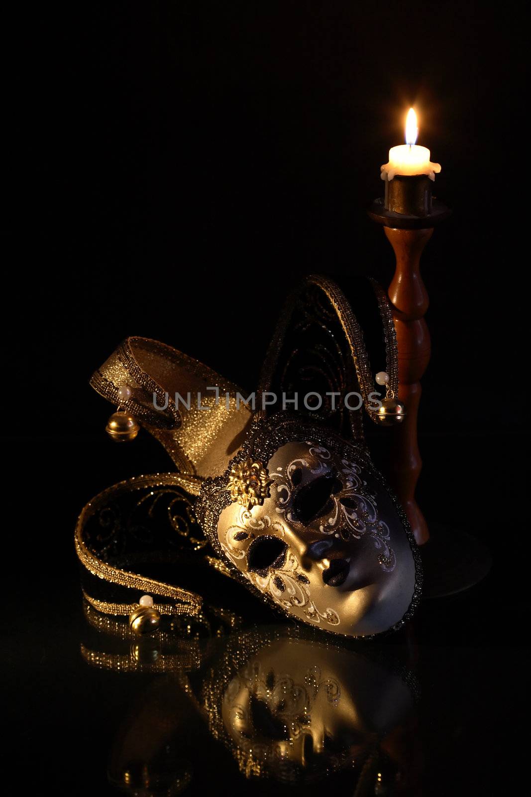 Beautiful classical venetian mask lying near lighting candle on dark background