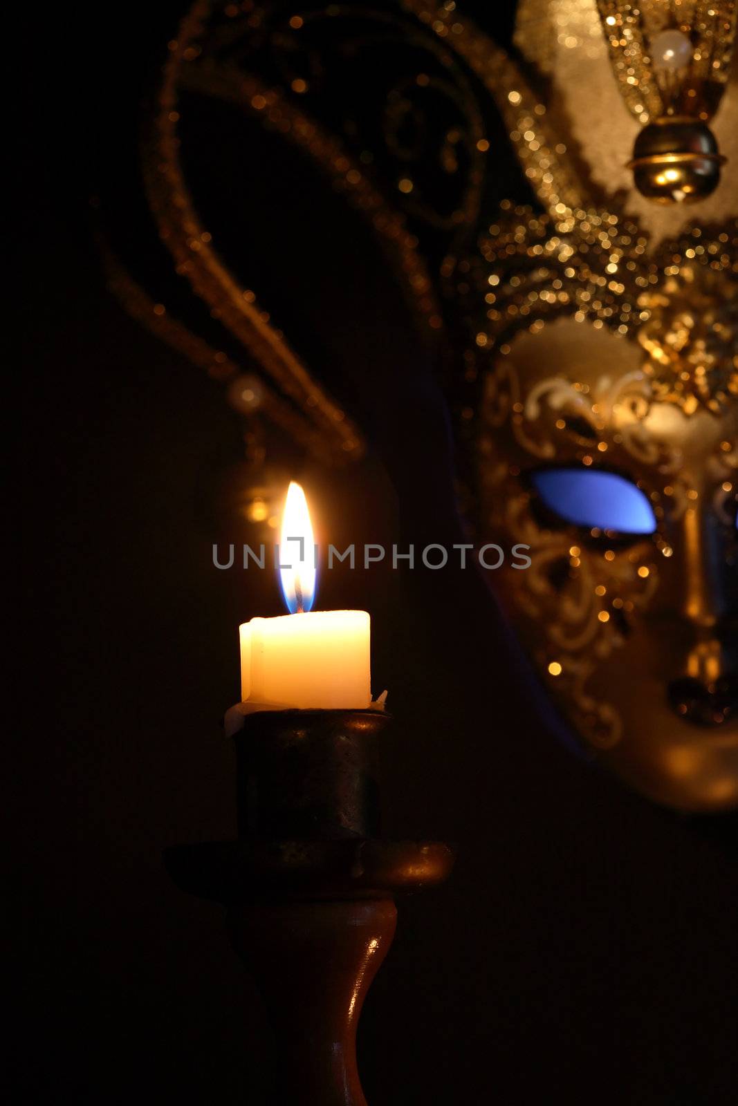 Lighting candle against beautiful classical venetian mask on dark background