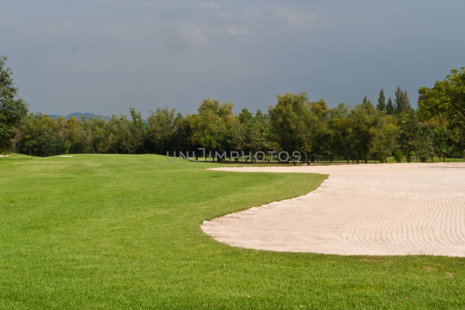 The golf course, grass and sand on blue sky.