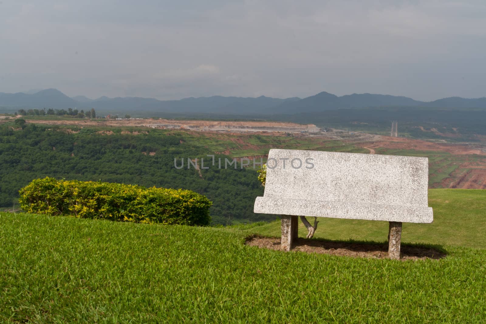 Cement bench on green grass and sky background