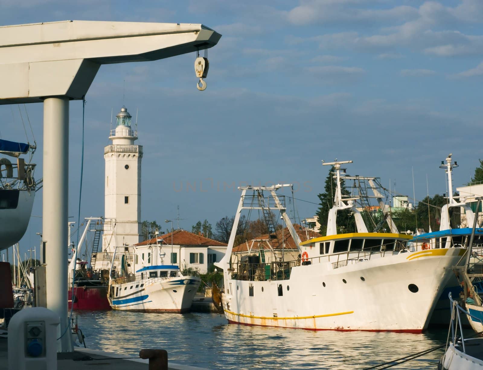 Fishing boats and a lighthouse in the port of Rimini in the sunset