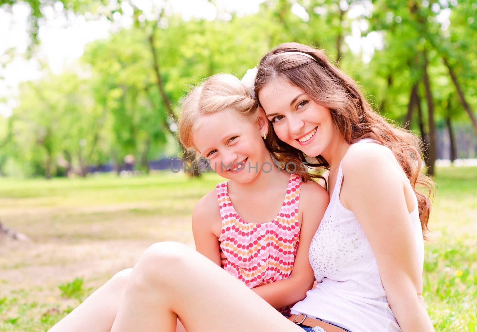 mother and daughter sitting together on the grass, and spend time with family