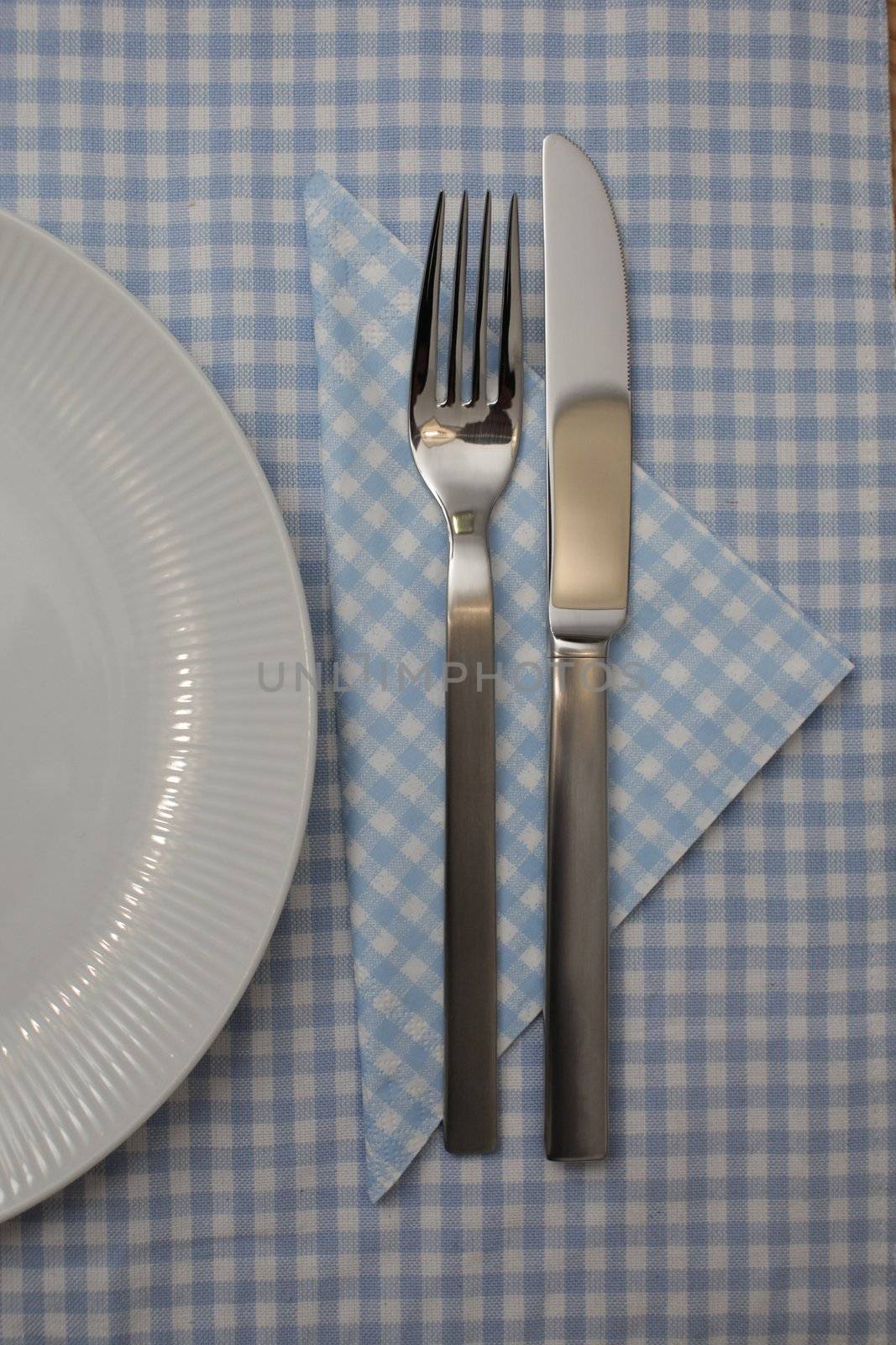knife fork and a white plate on a wooden background