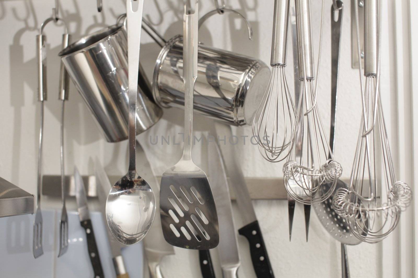 Rack of kitchen utensils isolated on white. Stainless steel