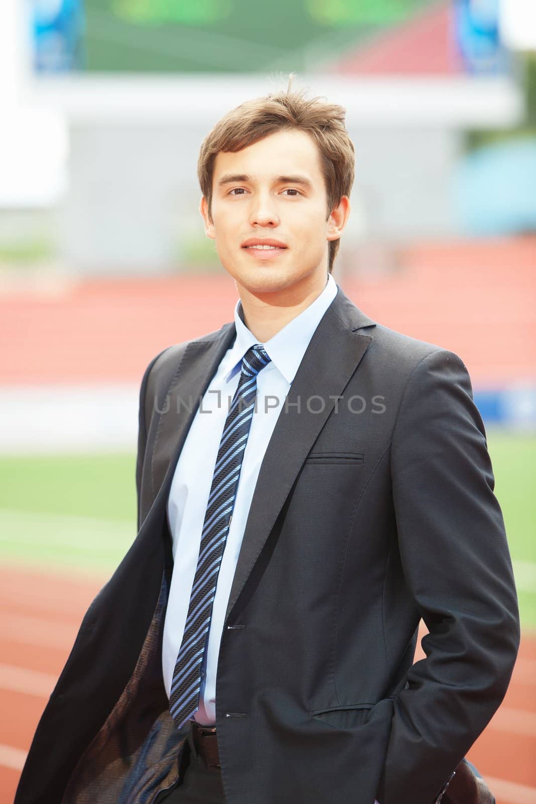 Satisfied smiling businessman standing in the summer outdoors.