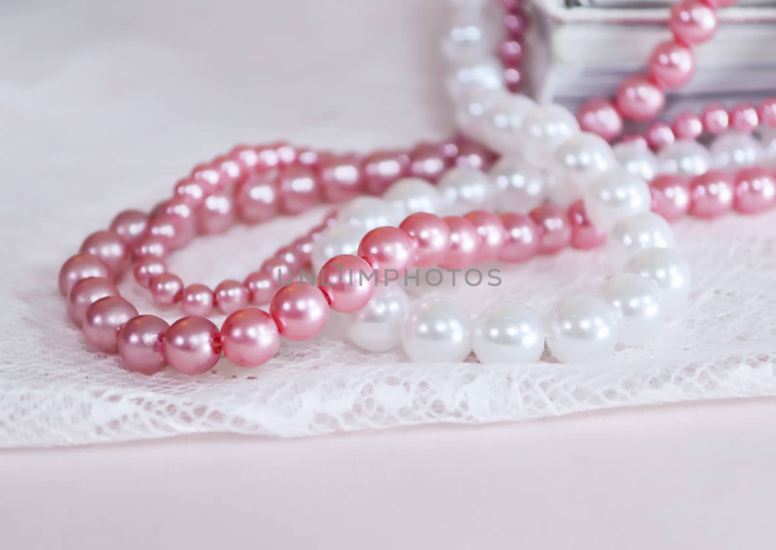 White and pink pearl necklace on top of books