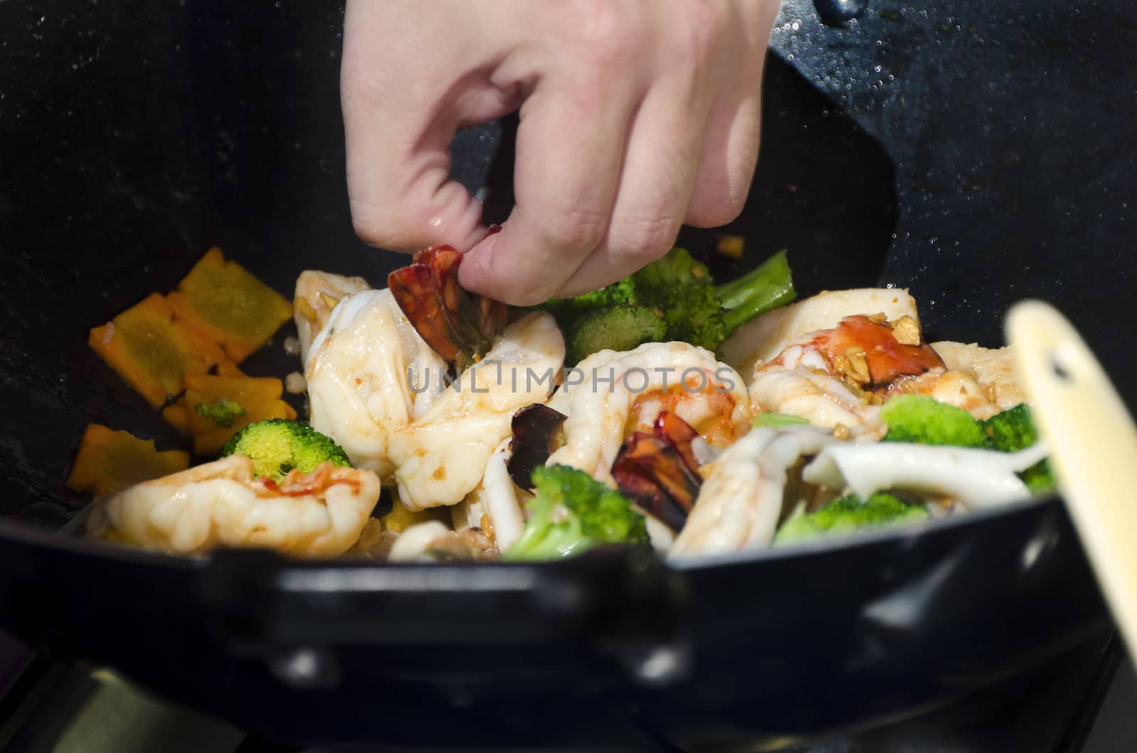 Close-up of shrimps and vegetables in wok with wooden spoon