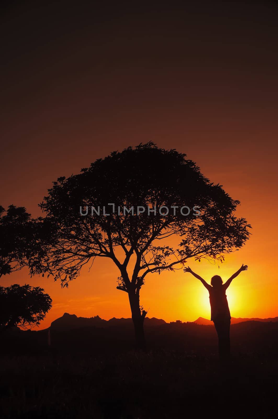 Woman stretches her arms to sky and sun