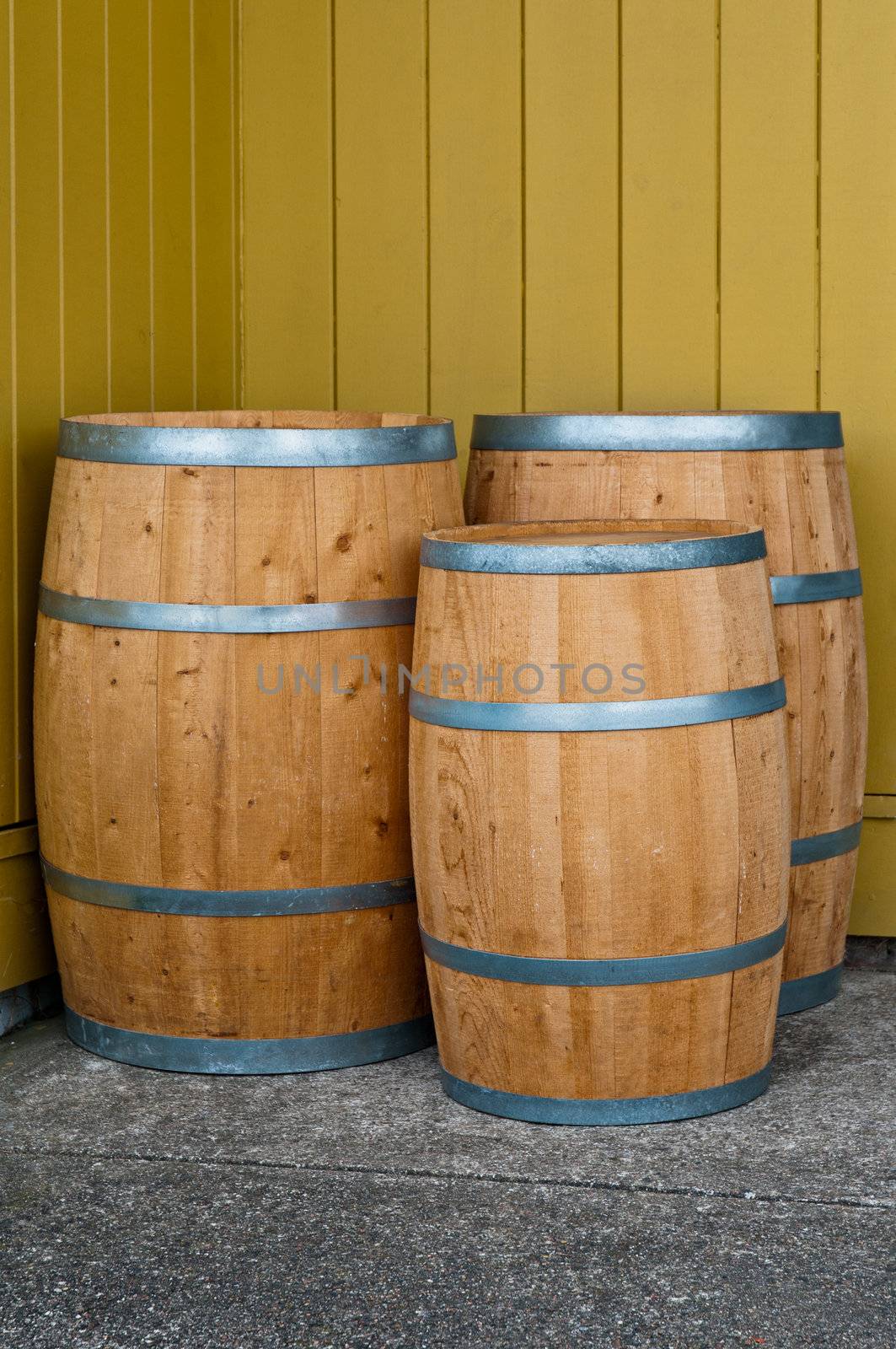 Three wooden barrels in front of a wooden wall