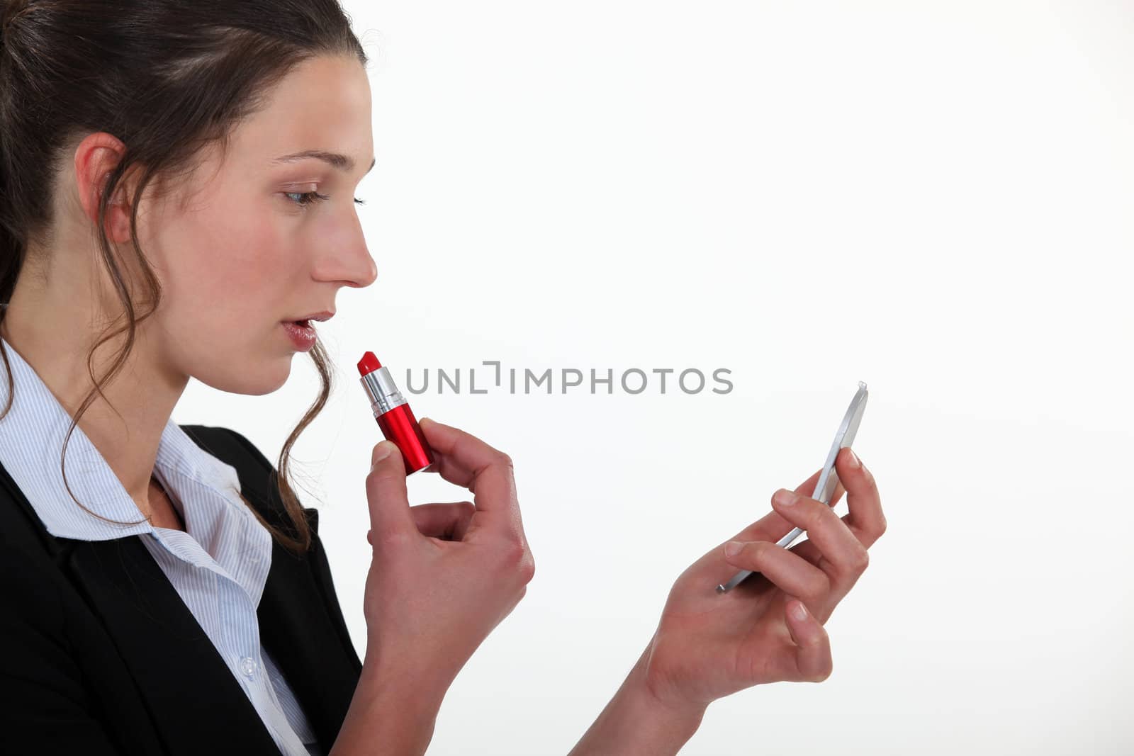 A businesswoman putting lipstick on. by phovoir