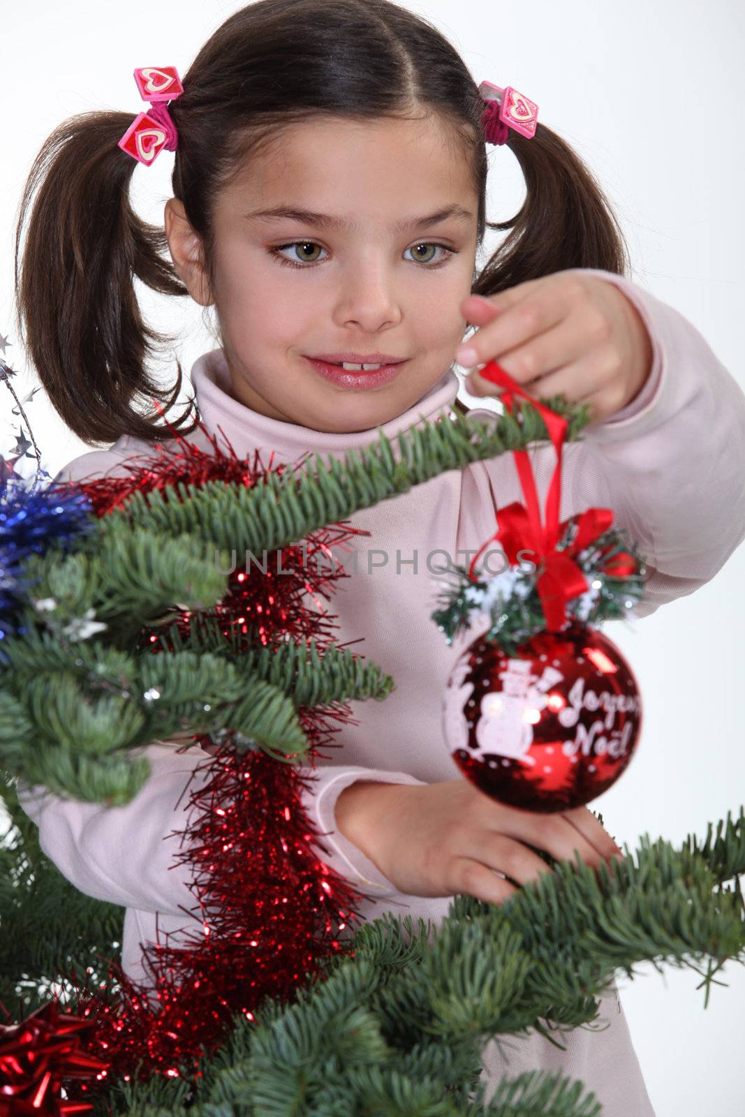 Young girl decorating a Christmas tree by phovoir