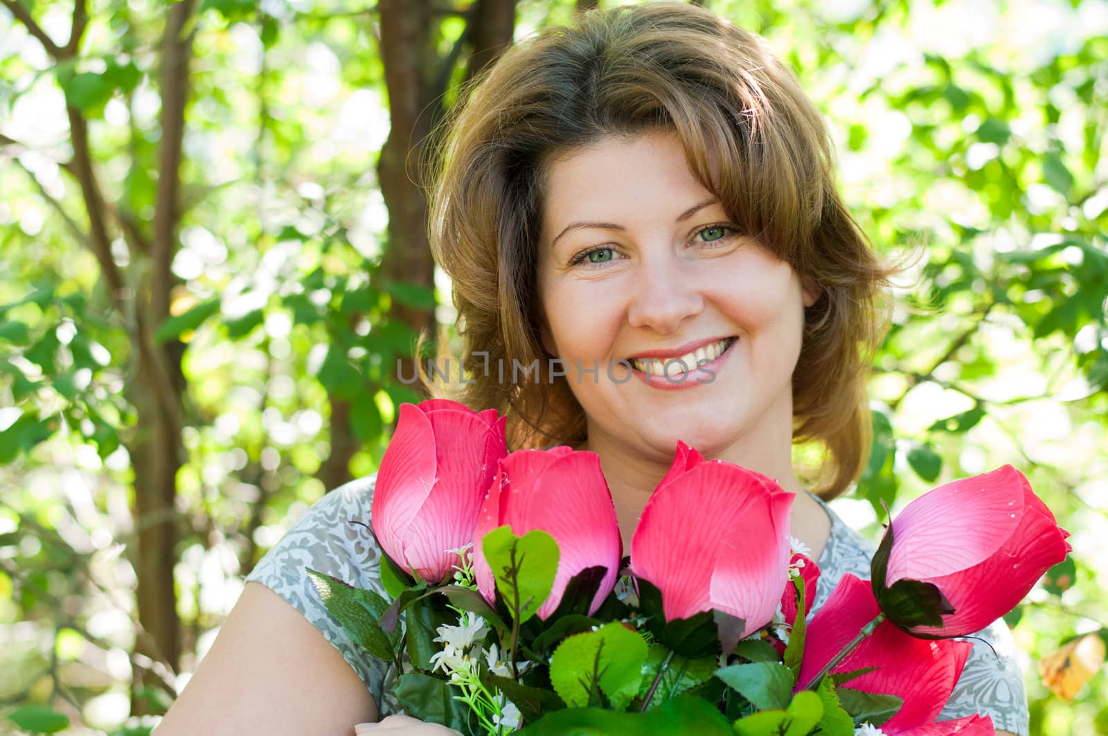 woman with a bouquet of artificial flowers in summer park by olgavolodina