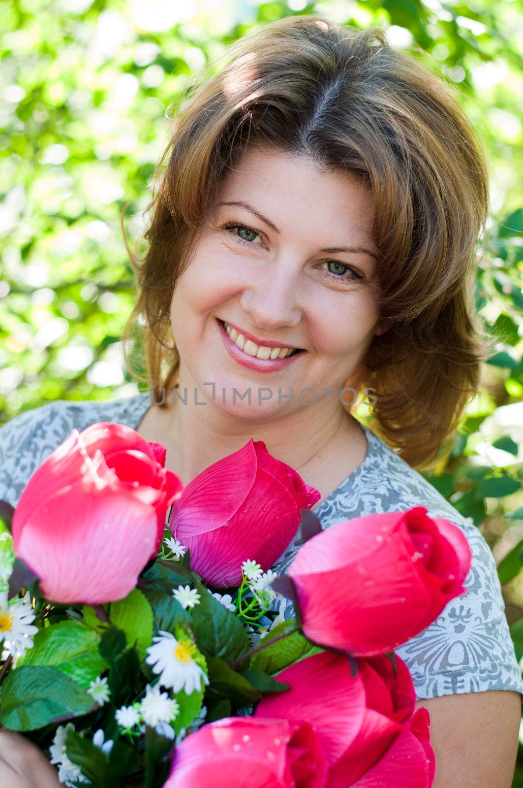woman with a bouquet of artificial flowers in summer park