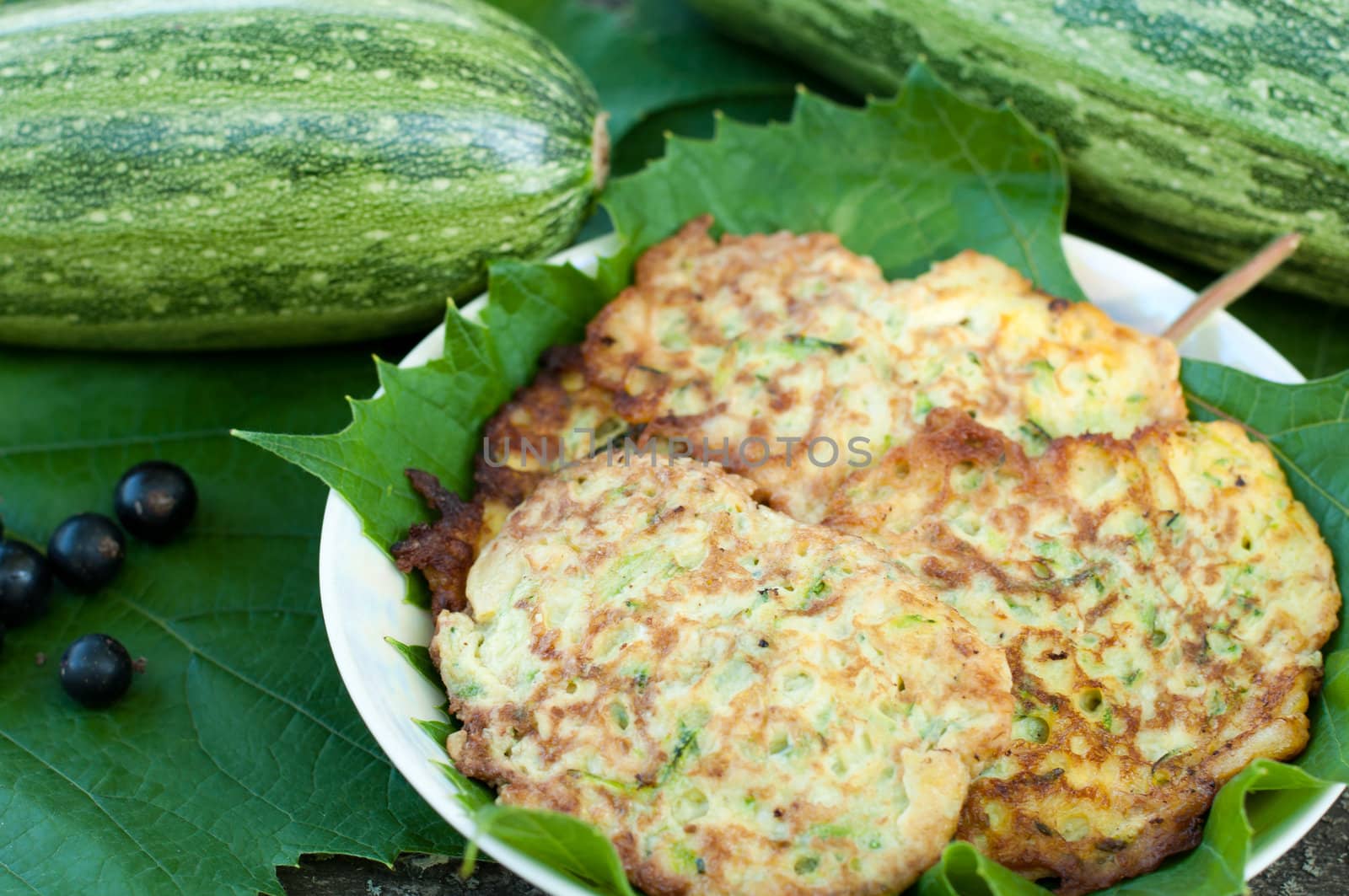 Pancakes with fresh zucchini on grape leaves by olgavolodina